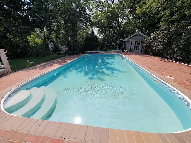 pool with an outbuilding, a storage structure, and a patio area