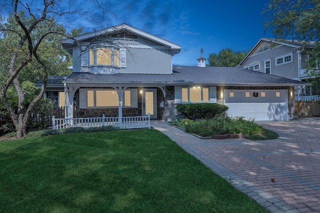 traditional-style house with stone siding, an attached garage, fence, decorative driveway, and a front lawn