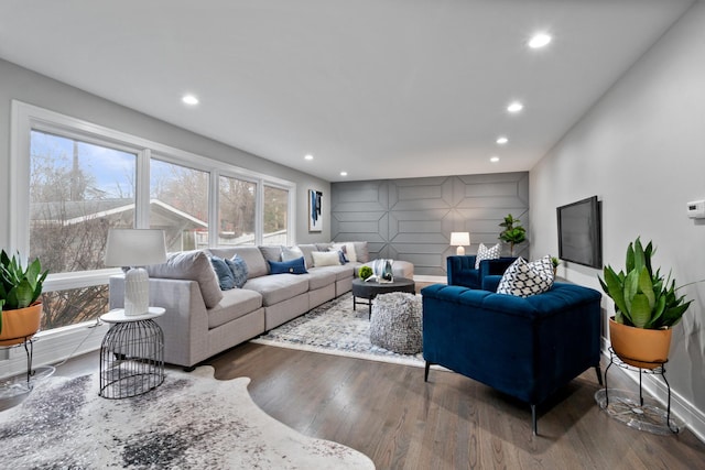 living area with dark wood-style floors, an accent wall, baseboards, and recessed lighting