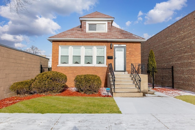 view of front facade featuring brick siding, fence, and a front lawn