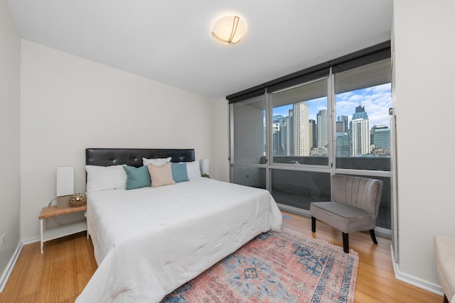 bedroom featuring baseboards, wood finished floors, and a city view