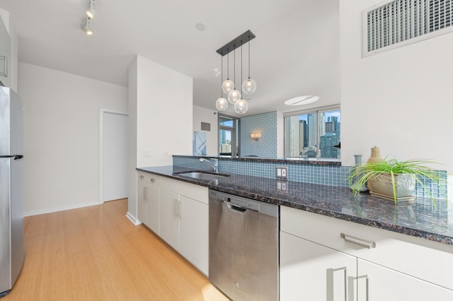 kitchen featuring visible vents, appliances with stainless steel finishes, white cabinetry, pendant lighting, and a sink