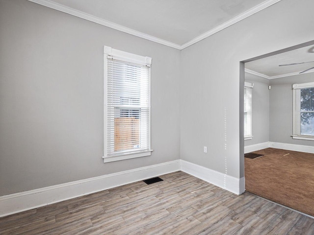 unfurnished room with ornamental molding, visible vents, light wood-style flooring, and baseboards