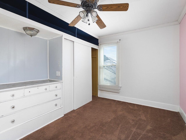 unfurnished bedroom with a ceiling fan, baseboards, a closet, dark colored carpet, and crown molding