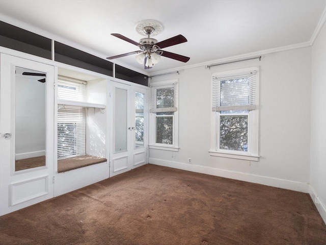 unfurnished room featuring crown molding, dark colored carpet, ceiling fan, and baseboards