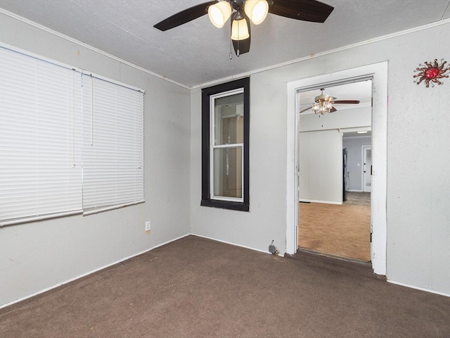 empty room featuring a textured ceiling, dark colored carpet, and crown molding