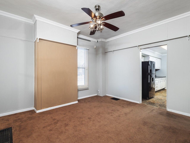 unfurnished bedroom featuring baseboards, dark colored carpet, crown molding, and freestanding refrigerator