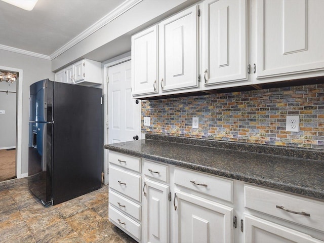 kitchen with baseboards, decorative backsplash, crown molding, white cabinetry, and black fridge