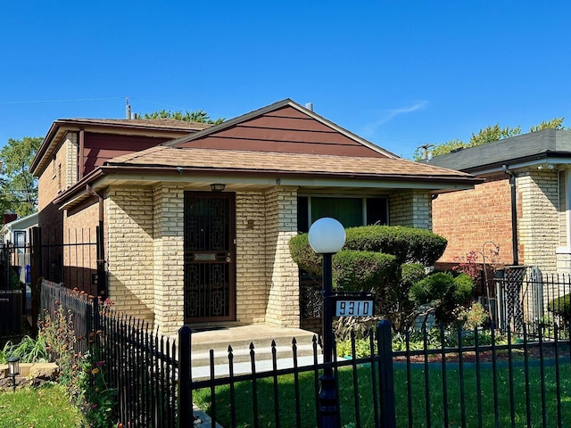 bungalow-style house featuring roof with shingles, brick siding, and a fenced front yard