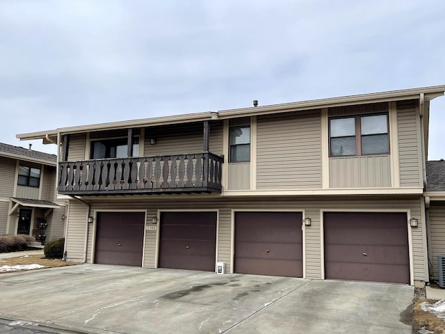 multi unit property featuring a garage, a balcony, and driveway