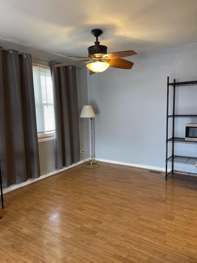 empty room with visible vents, ceiling fan, light wood-style flooring, and baseboards