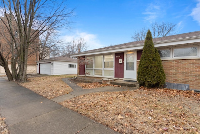 ranch-style home featuring a garage, an outbuilding, brick siding, and driveway