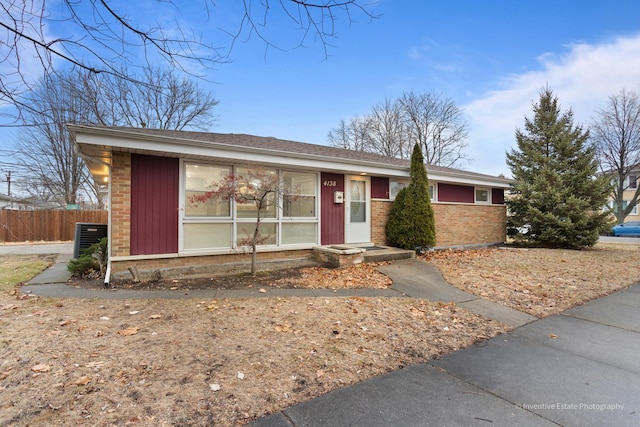 ranch-style house featuring brick siding, fence, and central AC