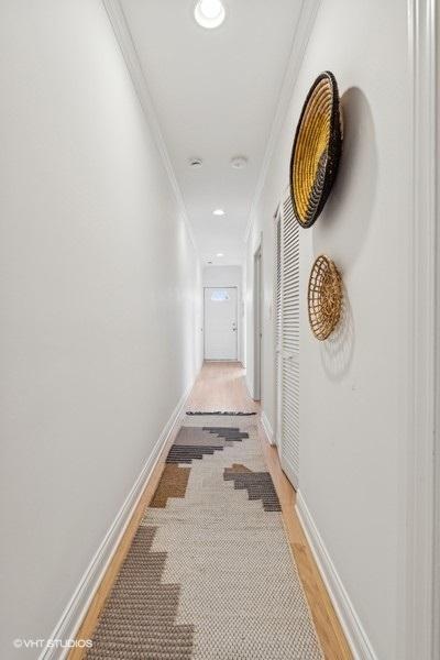 hall with light wood-type flooring, crown molding, baseboards, and recessed lighting