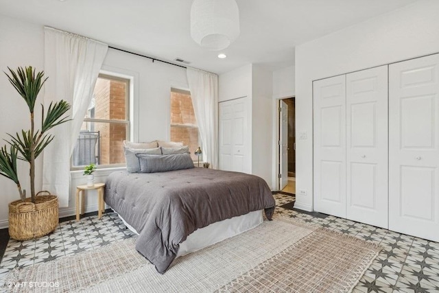 bedroom featuring two closets, visible vents, and tile patterned floors