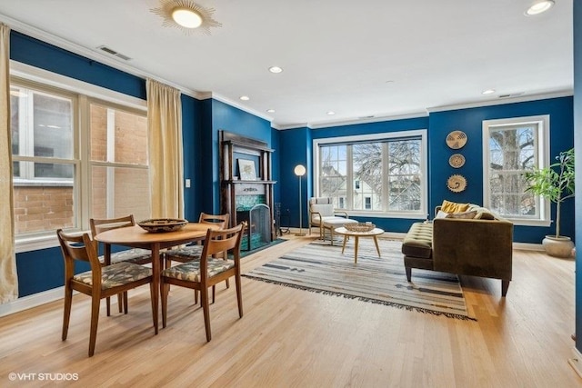 interior space with light wood-style floors, a fireplace with flush hearth, visible vents, and a healthy amount of sunlight