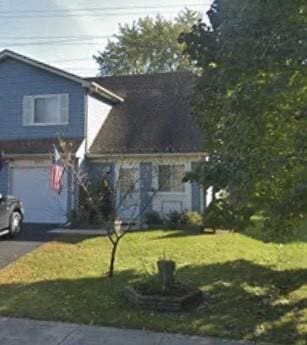 view of front of house with aphalt driveway, a front lawn, and an attached garage