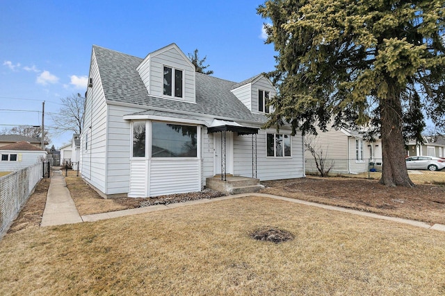 cape cod-style house with a shingled roof, fence, and a front yard