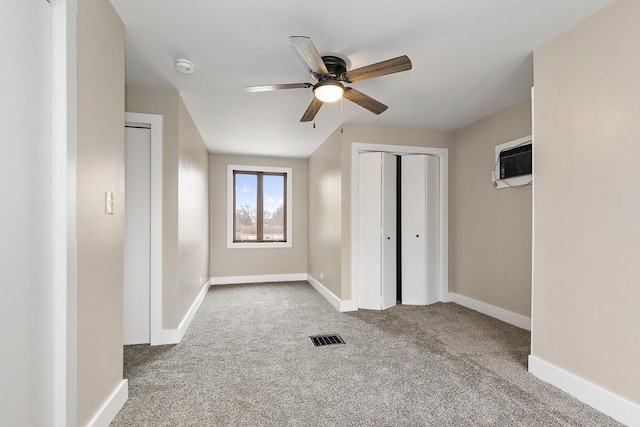 unfurnished bedroom featuring carpet, baseboards, visible vents, and a wall mounted AC