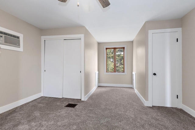 unfurnished bedroom with carpet flooring, visible vents, baseboards, an AC wall unit, and a closet