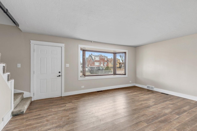 entrance foyer featuring a barn door, visible vents, stairway, wood finished floors, and a textured ceiling