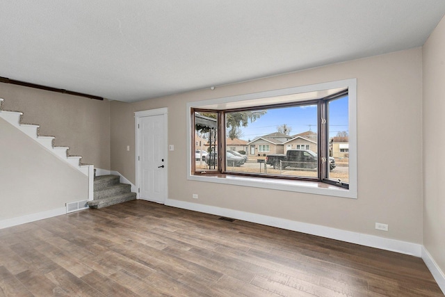 interior space with visible vents, stairway, baseboards, and wood finished floors