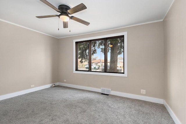 carpeted empty room featuring baseboards, ceiling fan, visible vents, and crown molding