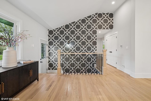 empty room featuring light wood-style flooring, high vaulted ceiling, and baseboards