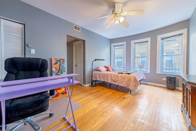 bedroom with light wood-style floors, visible vents, baseboards, and a ceiling fan