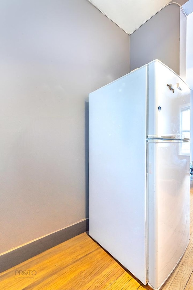 kitchen with baseboards, wood finished floors, and freestanding refrigerator