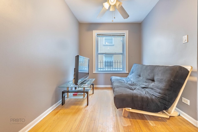 sitting room featuring ceiling fan, light wood-style flooring, and baseboards