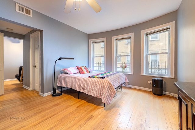 bedroom featuring light wood-style floors, baseboards, visible vents, and a ceiling fan