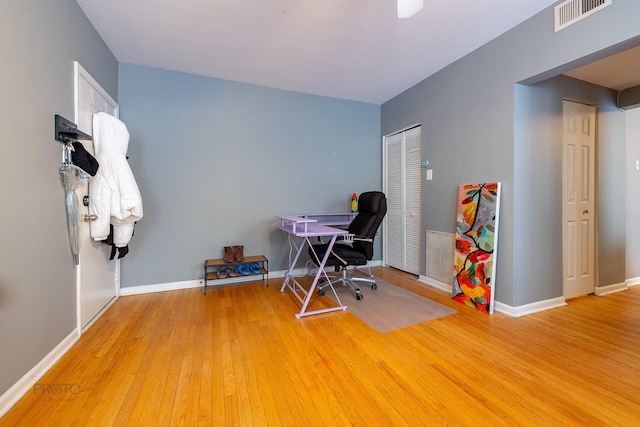 office space featuring wood finished floors, visible vents, and baseboards