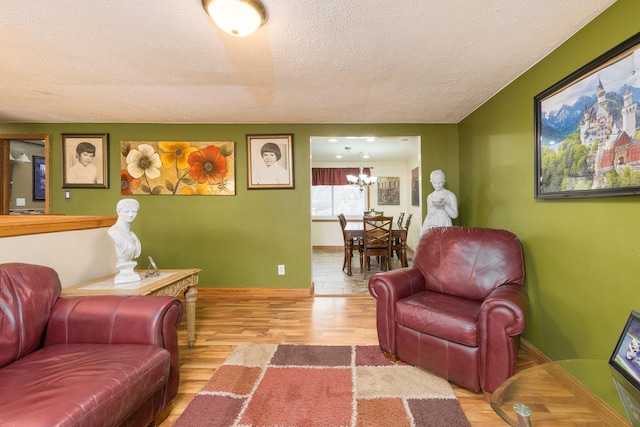 living room with baseboards, a textured ceiling, an inviting chandelier, and wood finished floors