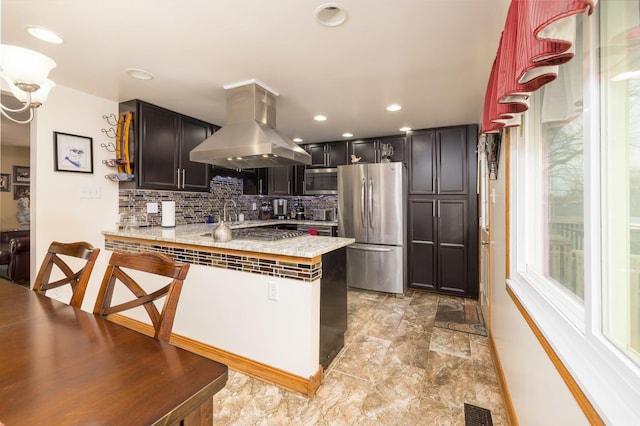 kitchen with island range hood, a peninsula, visible vents, appliances with stainless steel finishes, and decorative backsplash