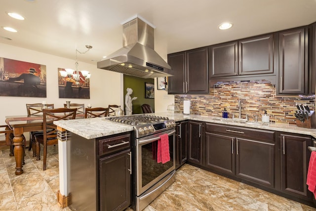 kitchen featuring stainless steel gas stove, a peninsula, a sink, range hood, and backsplash