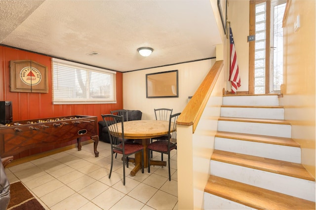 tiled dining room featuring visible vents, plenty of natural light, stairway, and a textured ceiling