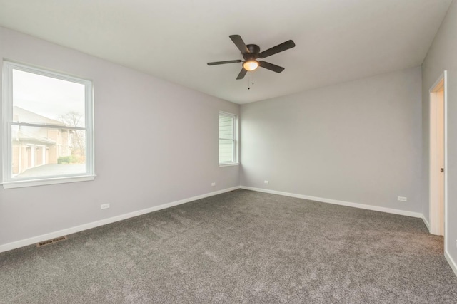 carpeted spare room featuring a ceiling fan, visible vents, and baseboards