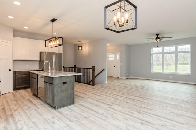 kitchen with light wood-style flooring, recessed lighting, baseboards, appliances with stainless steel finishes, and an island with sink