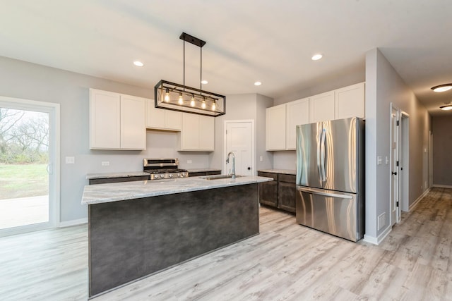 kitchen featuring stainless steel appliances, light stone counters, light wood-type flooring, and a sink