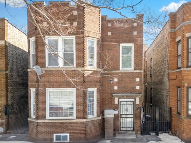 view of front facade with a gate and brick siding