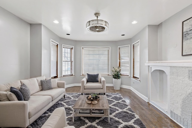 living room featuring dark wood-style flooring, recessed lighting, a fireplace, and baseboards