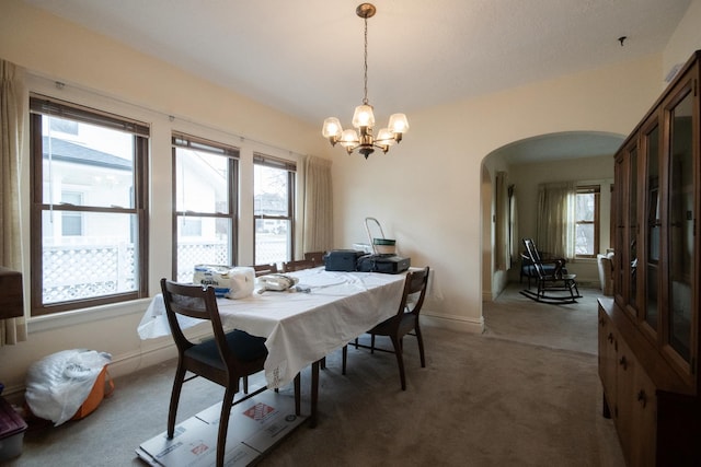 dining area featuring arched walkways, light carpet, a notable chandelier, and baseboards