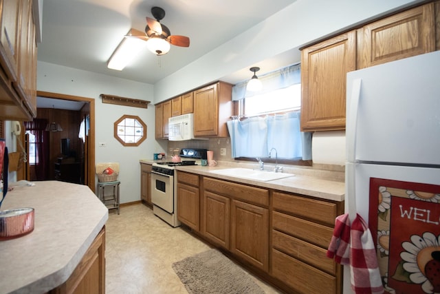 kitchen featuring white appliances, a sink, light countertops, light floors, and brown cabinetry