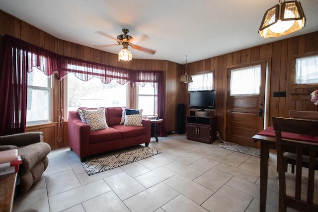 living room with ceiling fan, light tile patterned floors, and wooden walls