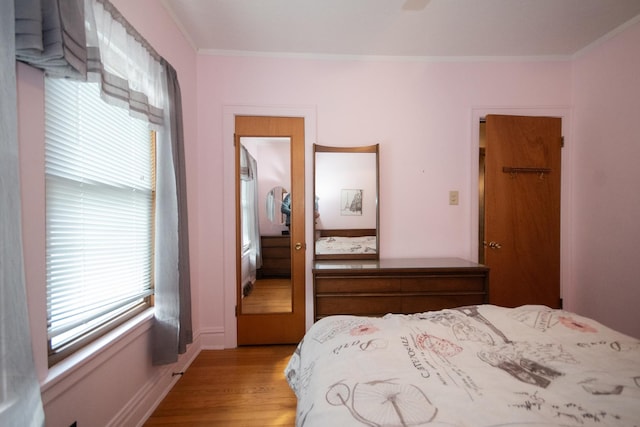 bedroom with ornamental molding and wood finished floors