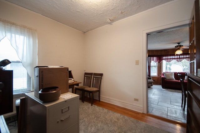 interior space with a textured ceiling, wood finished floors, and baseboards