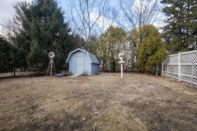 view of yard with a shed, fence, and an outbuilding