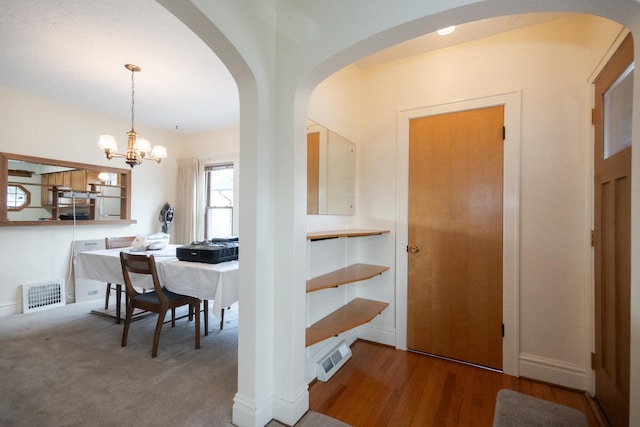 interior space featuring arched walkways, carpet floors, visible vents, and a notable chandelier