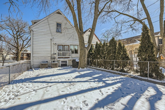 snow covered house with a fenced backyard